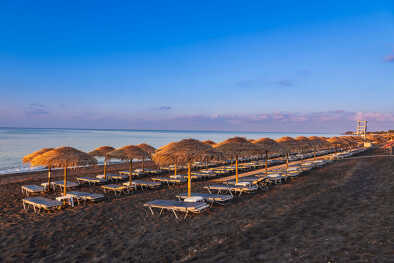 Perivolos beach on Santorini island in Greece at sunrise. The background is a blue sky with white clouds Perivolos beach on Santorini island in Greece at sunrise. The background is a blue sky with white clouds