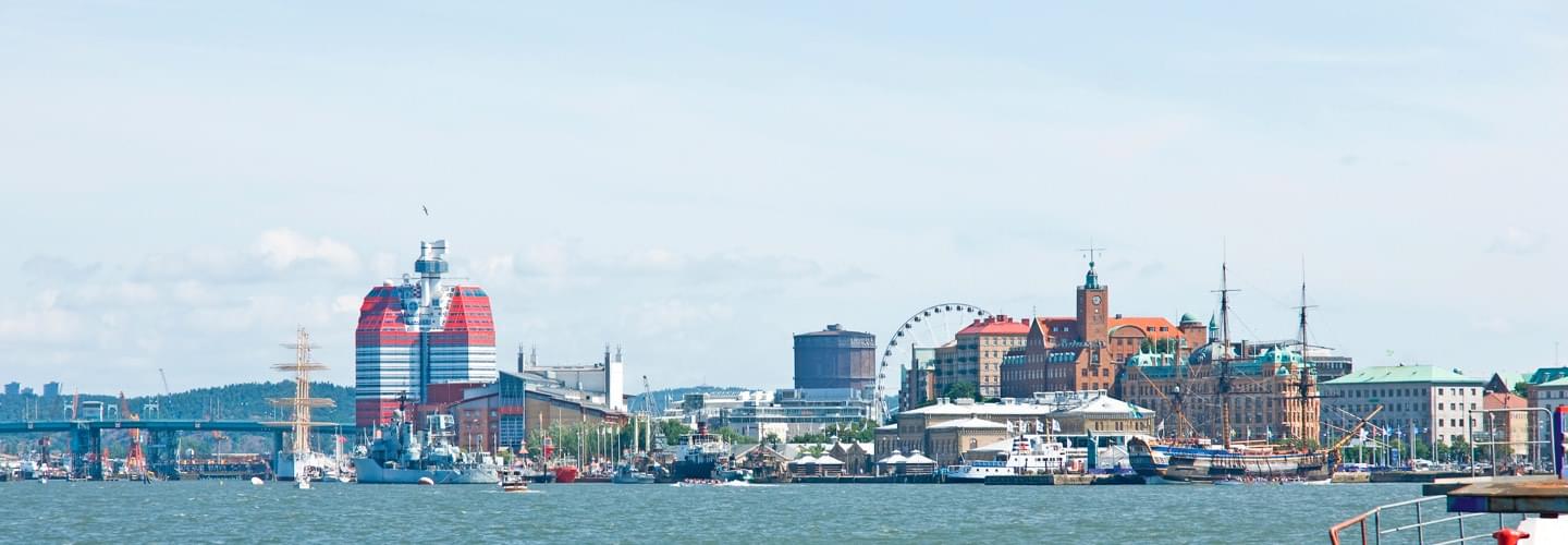 Photo of Gothenburg in Sweden taken from a river with a red and white building on the left and a cathedral on the right