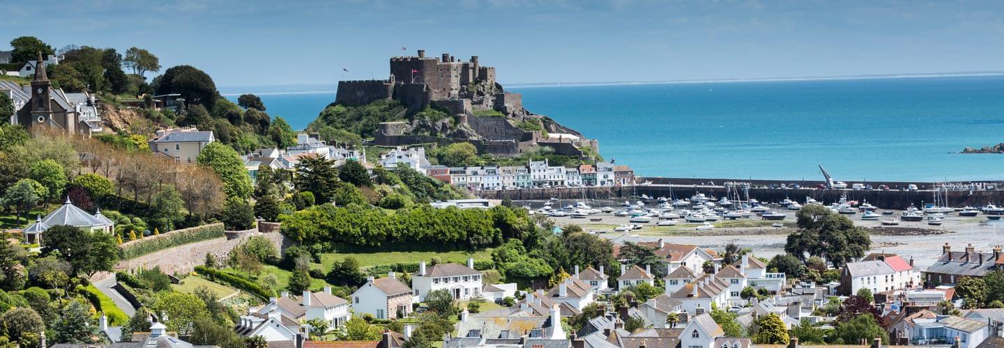 Aerial view of a port in Jersey Island with the Mont Orgueil Castle and the channel in background.