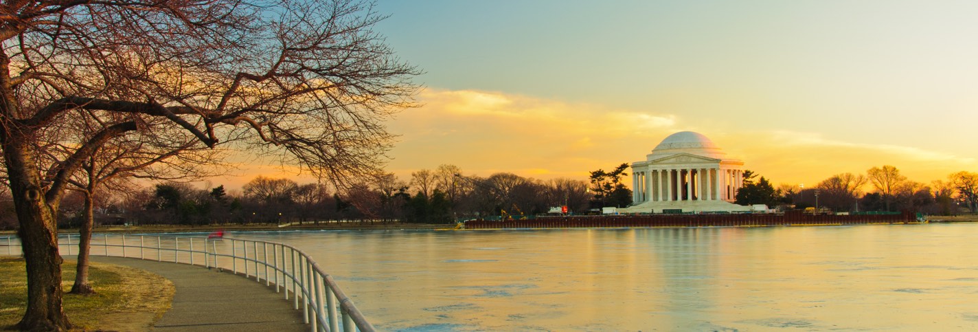 View of a river with a white building with columns in the background by sunset