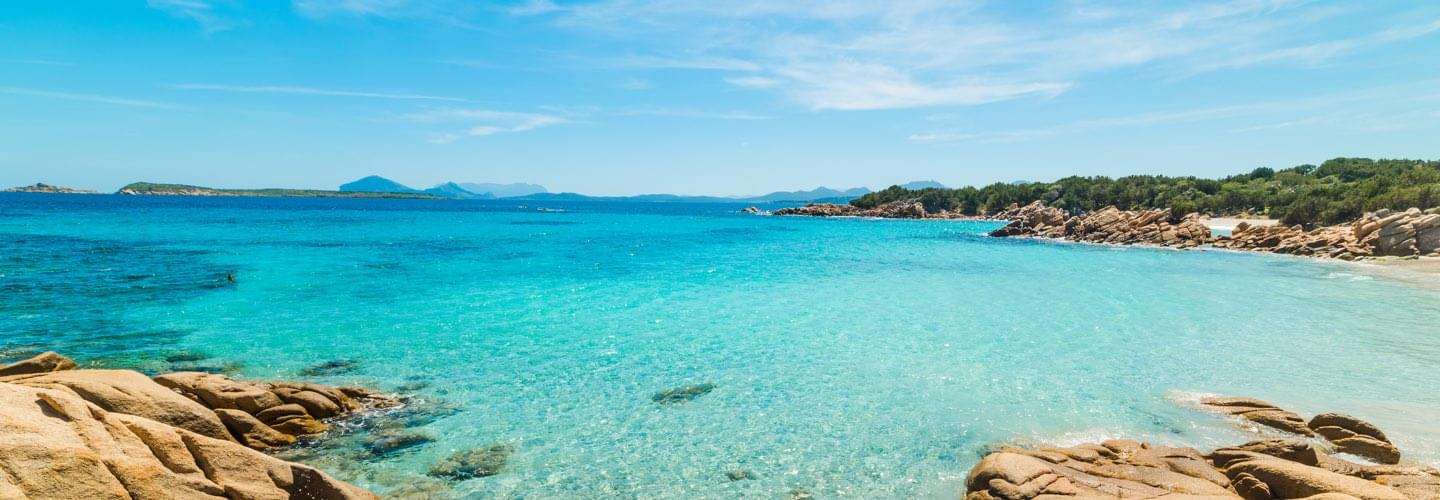 Lors d'une journée estivale paisible et ensoleillée, la Costa Smeralda à Olbia se révèle dans toute sa majesté, dévoilant des eaux turquoises d'une beauté spectaculaire.