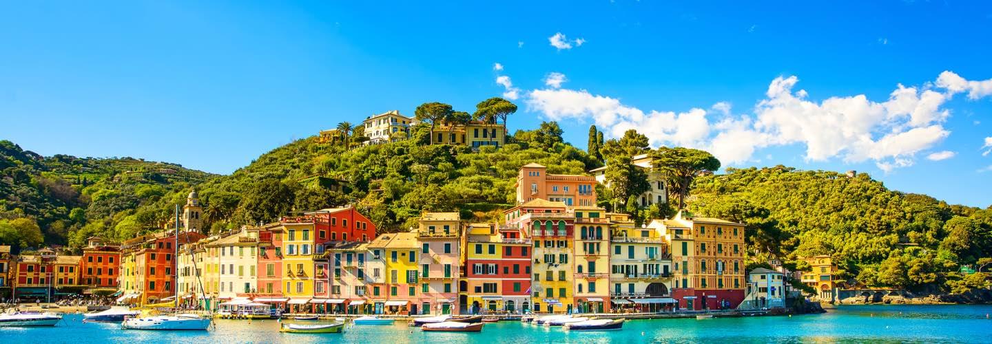 Daylight picture of Portofino in Italy with colored houses and boats with a blue cloudy sky