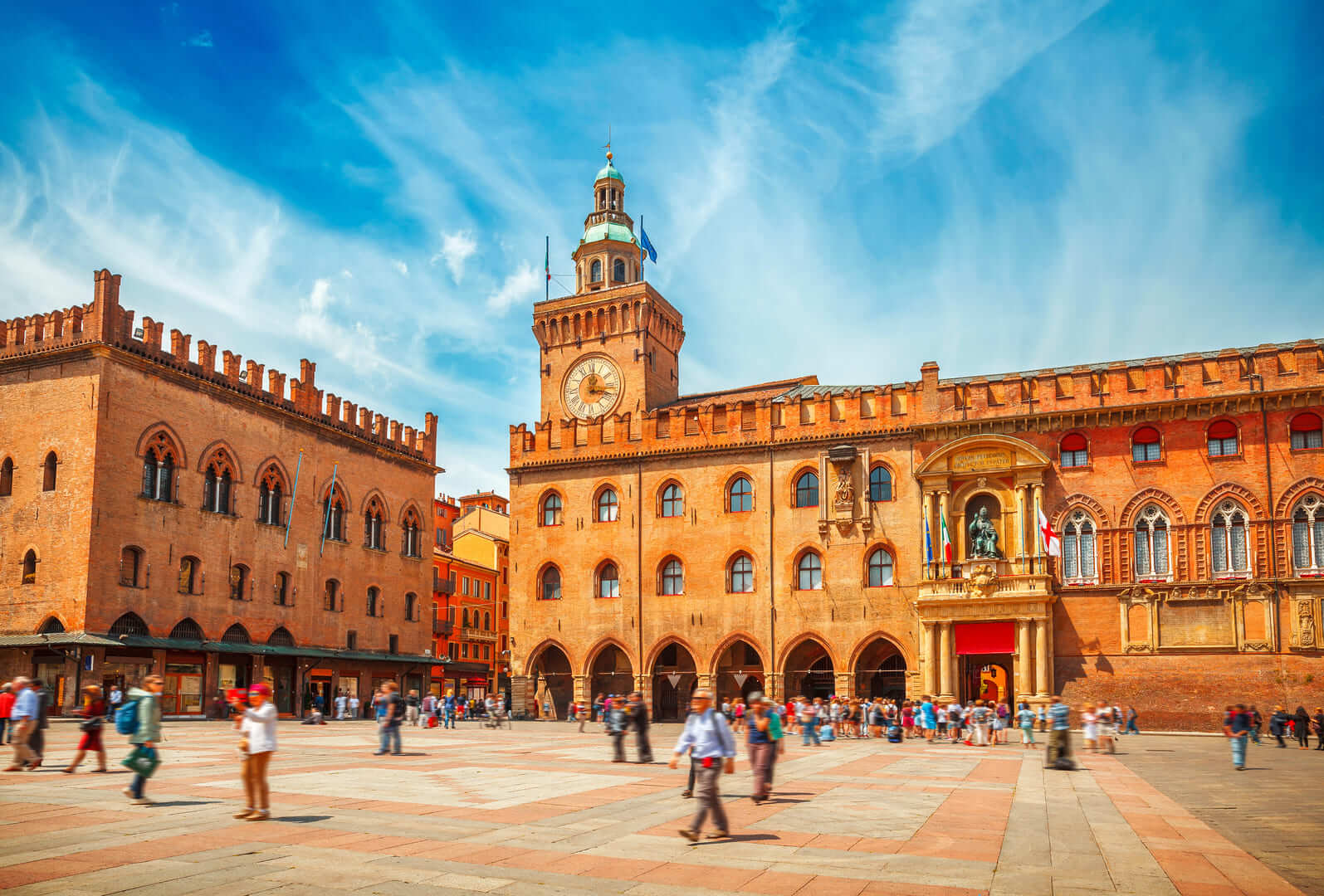 Italy Piazza Maggiore in Bologna old town tower of hall with big clock and blue sky on background. Antique buildings terracotta galleries
