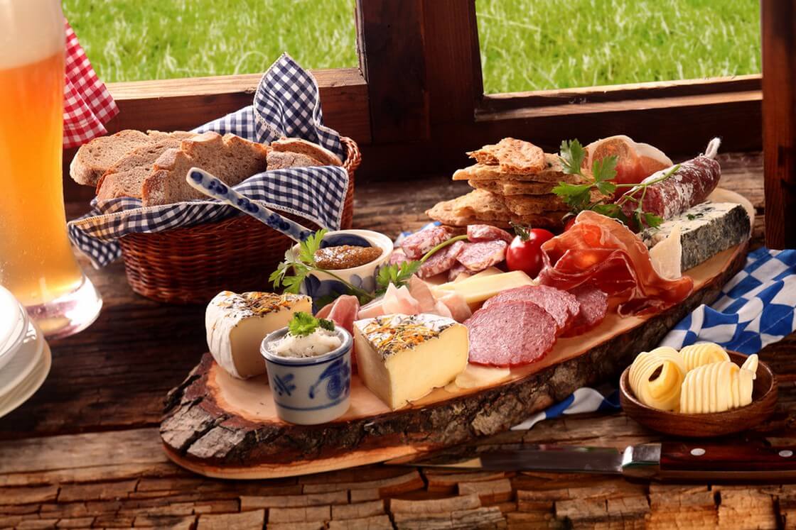 Delicious midday meal of a meat and cheese platter with a wide variety of cheeses, spicy sausage and ham served with a cold beer and fresh bread in a Bavarian tavern
