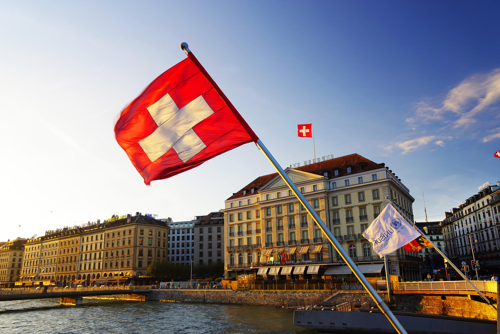Flag of the Geneva Canton and flag of Switerland in the city center of Geneva on the Mont Blanc Bridge (Pont du Mont Blanc) on the Leman lake
