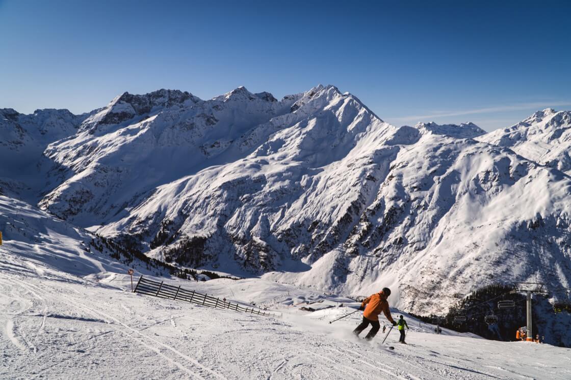 Skifahrer auf Pisten im Skigebiet St. Anton, Österreich schöne schneebedeckte Gipfel - Wintersport in Österreich