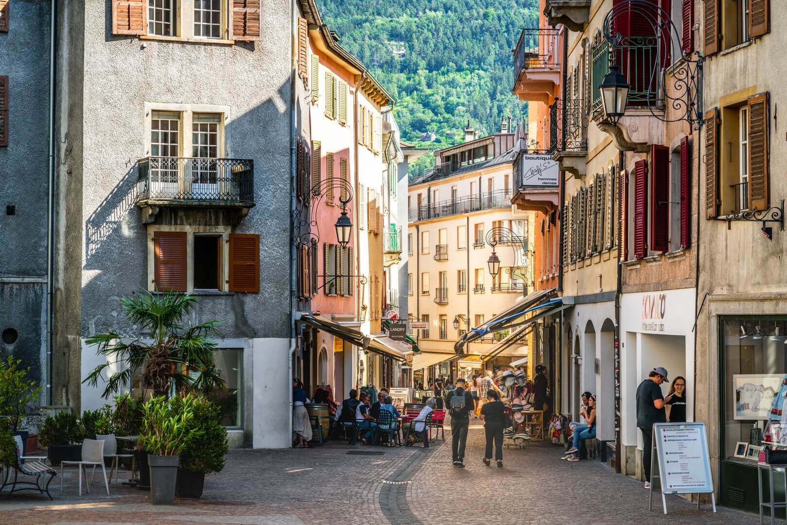 People in pedestrian laneway on sunny summer day with dramatic light in Sion old town Switzerland