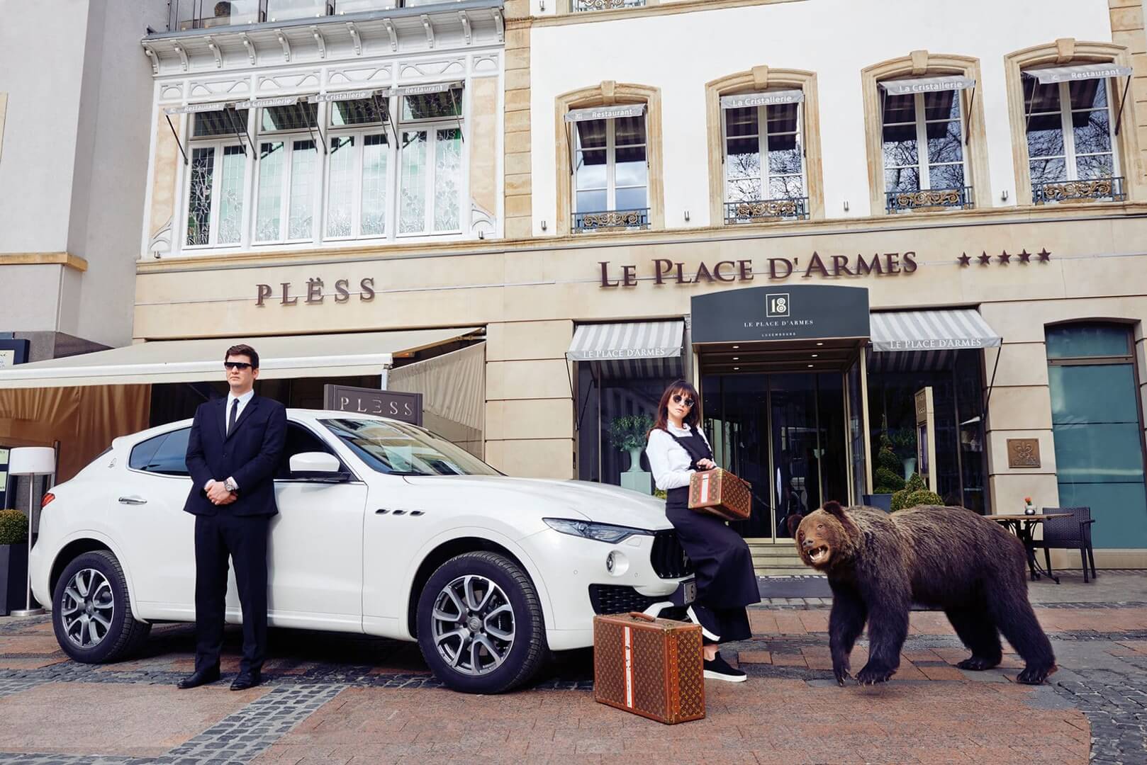 Front entrance of the "Le Palace D'Armes" hotel with a luxury car, 