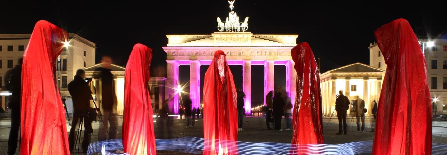 Five red silhouettes and lightning effects at Festival of lights in Berlin at Brandenburg Gate