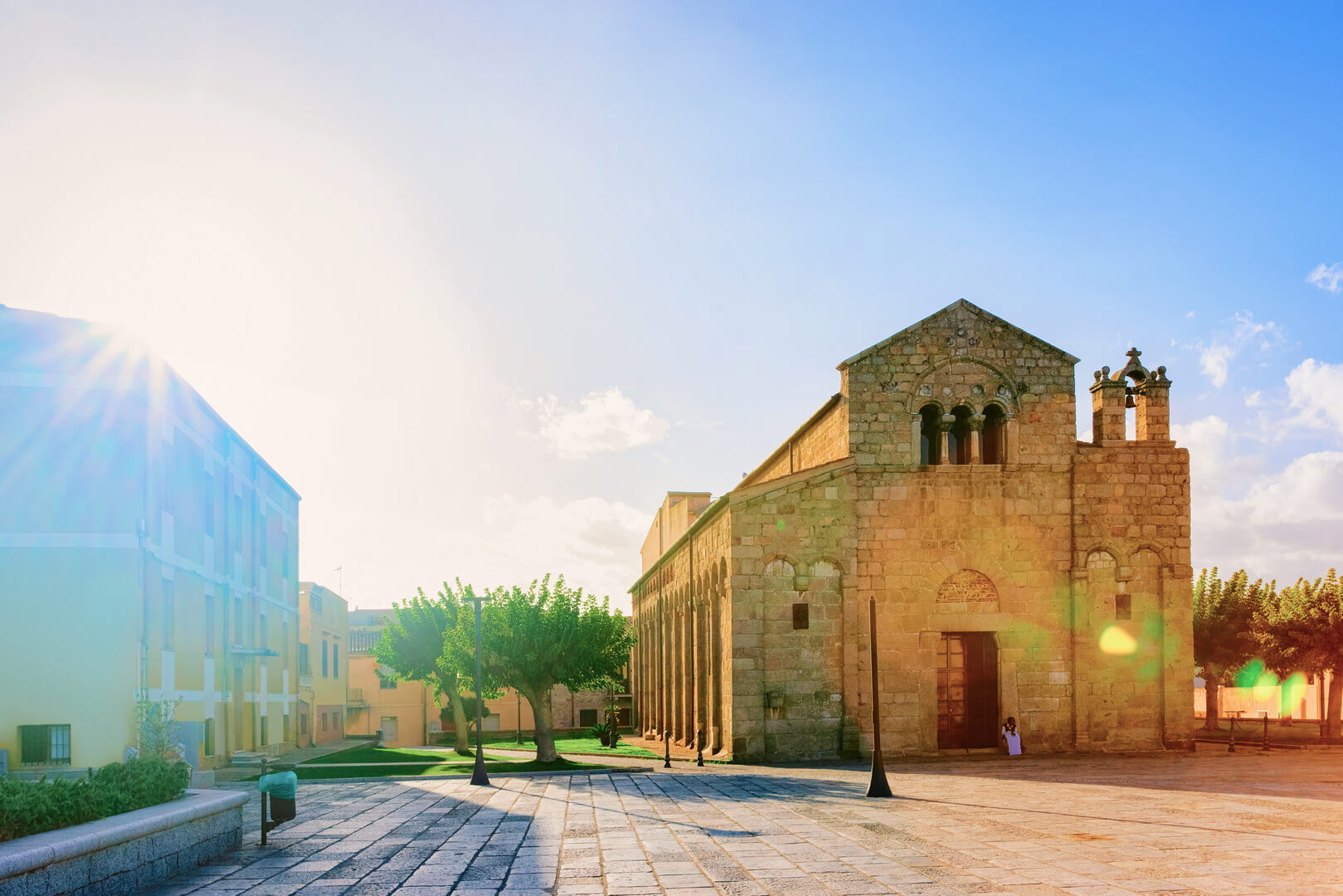 Basilica di San Simplicio nella città vecchia di Olbia sull'isola di Sardegna in Italia. Piazza con lanterne di strada e cattedrale nell'isola di Sardegna. Cielo blu e luce del sole
