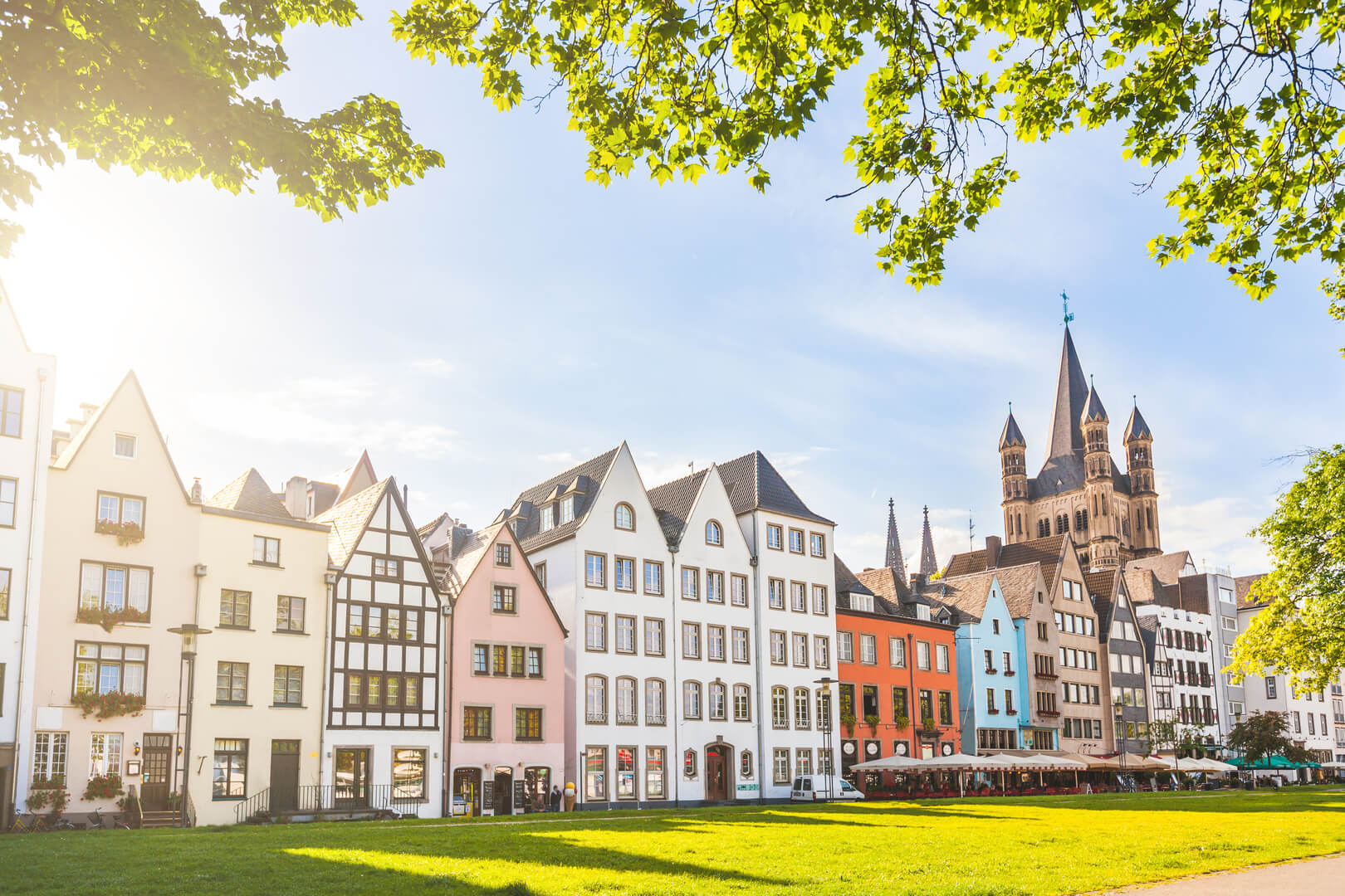 Maisons et parc à Cologne, en Allemagne. Beaucoup d'entre elles sont colorées, elles font face à un parc public avec de l'herbe verte et quelques arbres. On aperçoit un clocher en arrière-plan. Concepts de voyage et d'architecture.