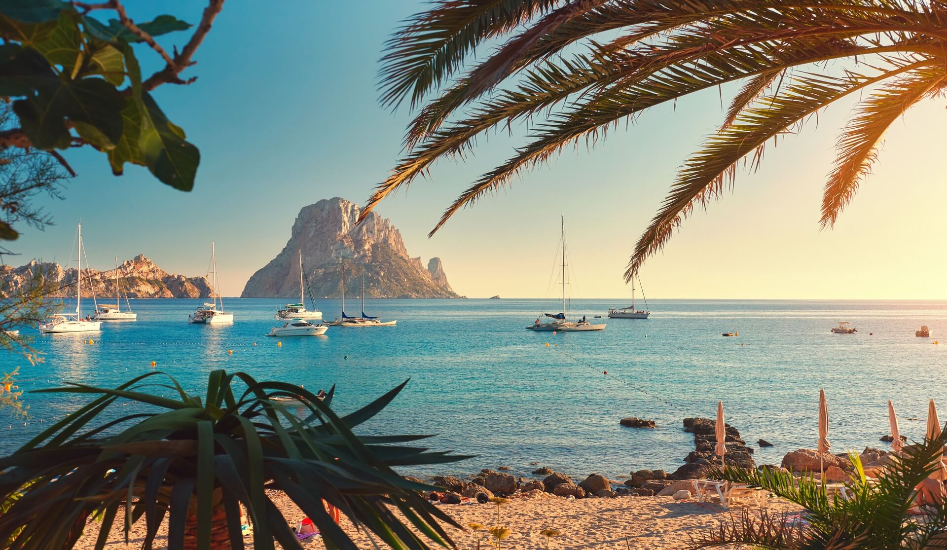 Famosa, vuota e bella spiaggia di Cala d'Hort, in estate molto popolare, costa sabbiosa hanno una fantastica vista della misteriosa isola di Es Vedra. Navi ormeggiate nella baia. Isola di Ibiza, Isole Baleari. Spagna