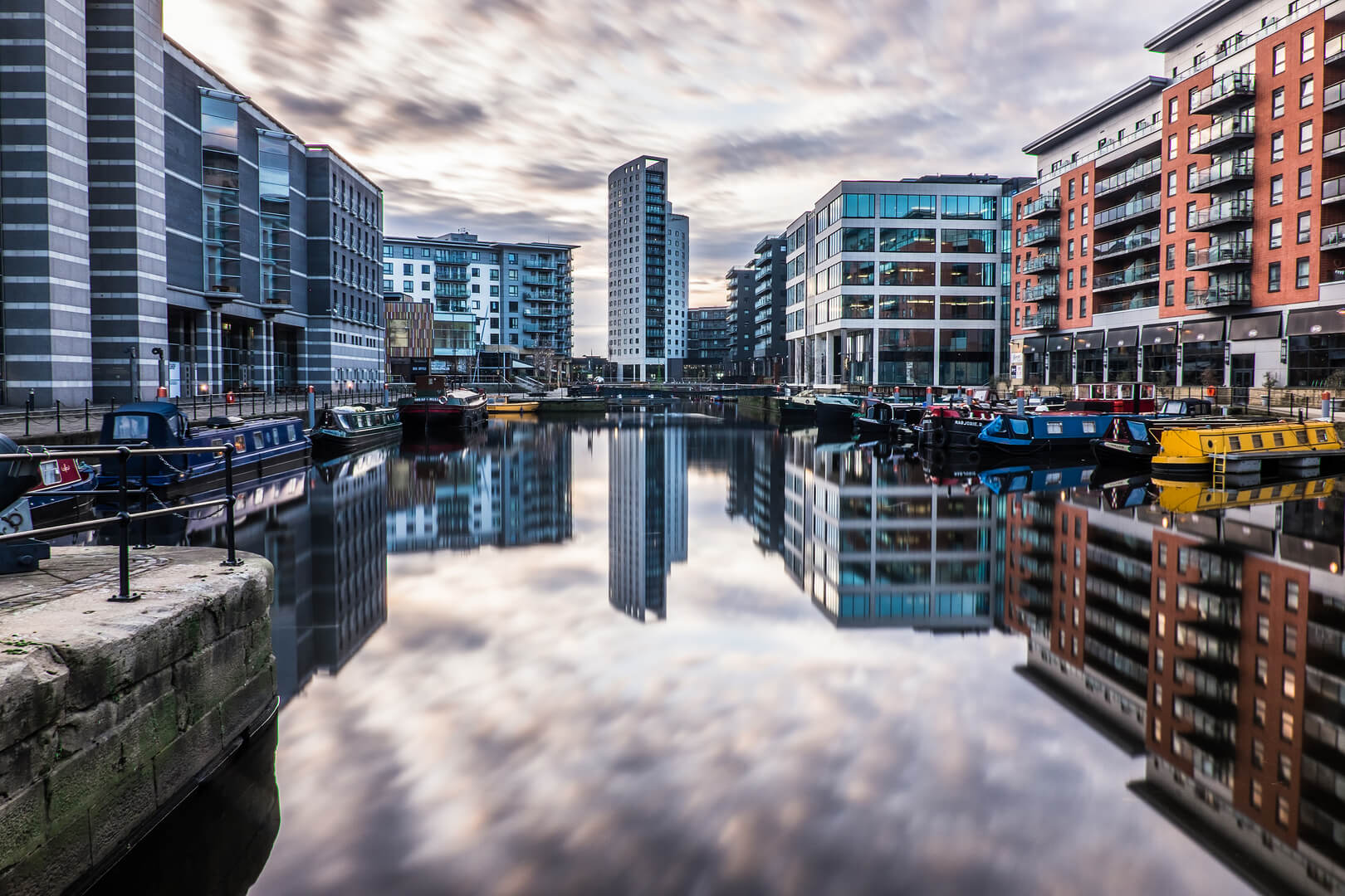 Leeds, West Yorkshire, Inghilterra, Gran Bretagna, dicembre 2016, architettura moderna con appartamenti e uffici utilizzando una lunga esposizione che mostra il movimento delle nuvole al Leeds Dock