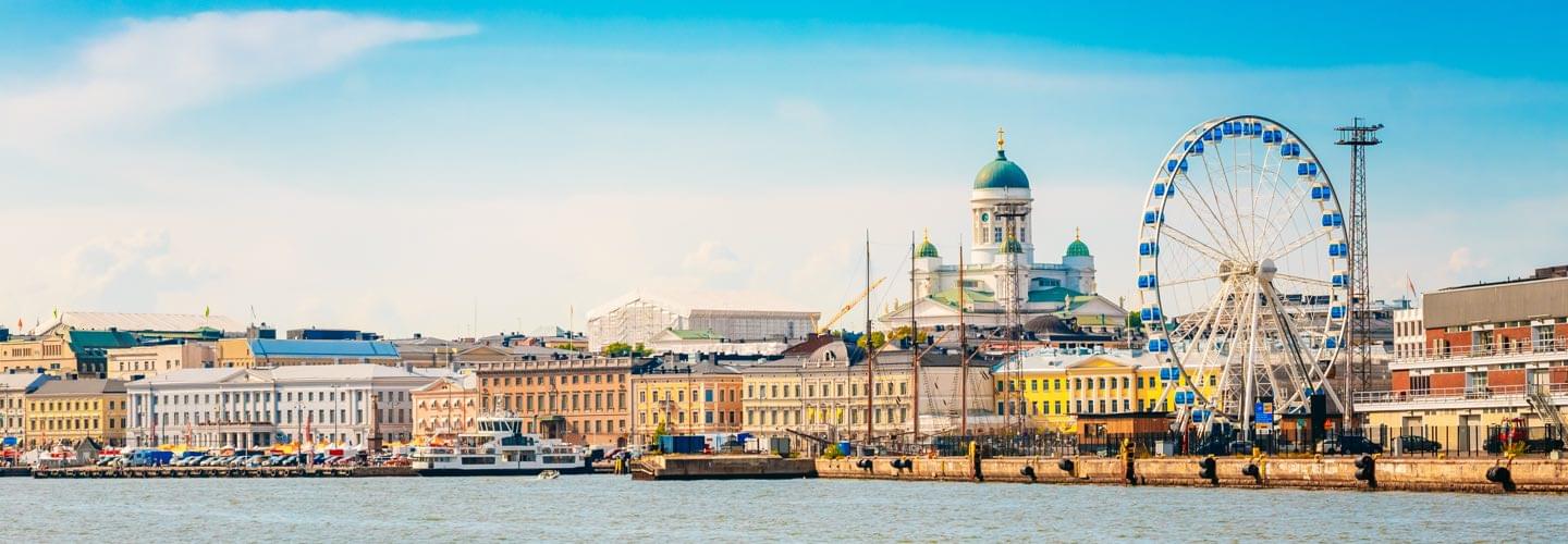 Foto della città di Helsinki, in primo piano un fiume con alcune barche, sullo sfondo la Cattedrale di Uspenski