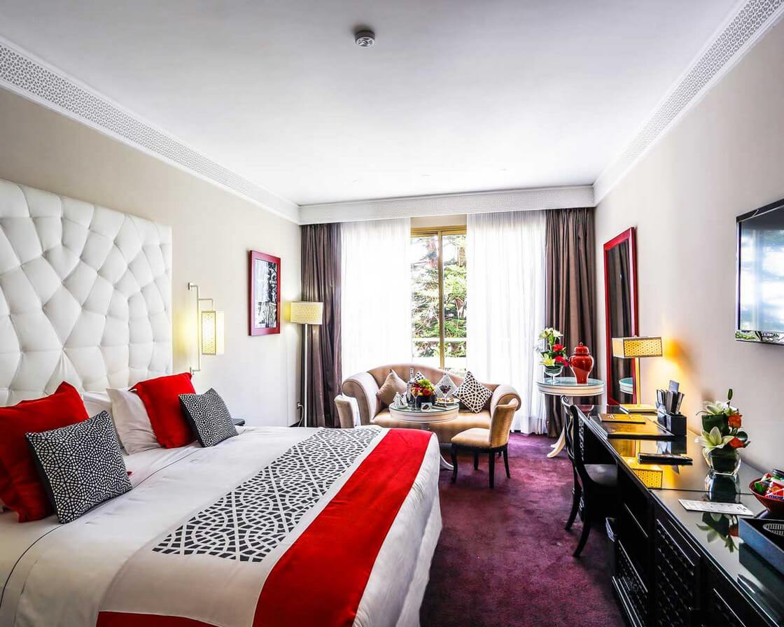 Zimmer mit Sofa und Schreibtisch sowie Kingsize-Bett im La Tour Hassan Palace