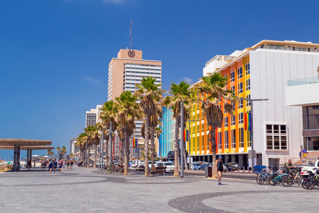 Blick von der Strandpromenade von Tel Aviv mit Hotelgebäuden, Residenzen und herumlaufenden und schwimmenden Menschen