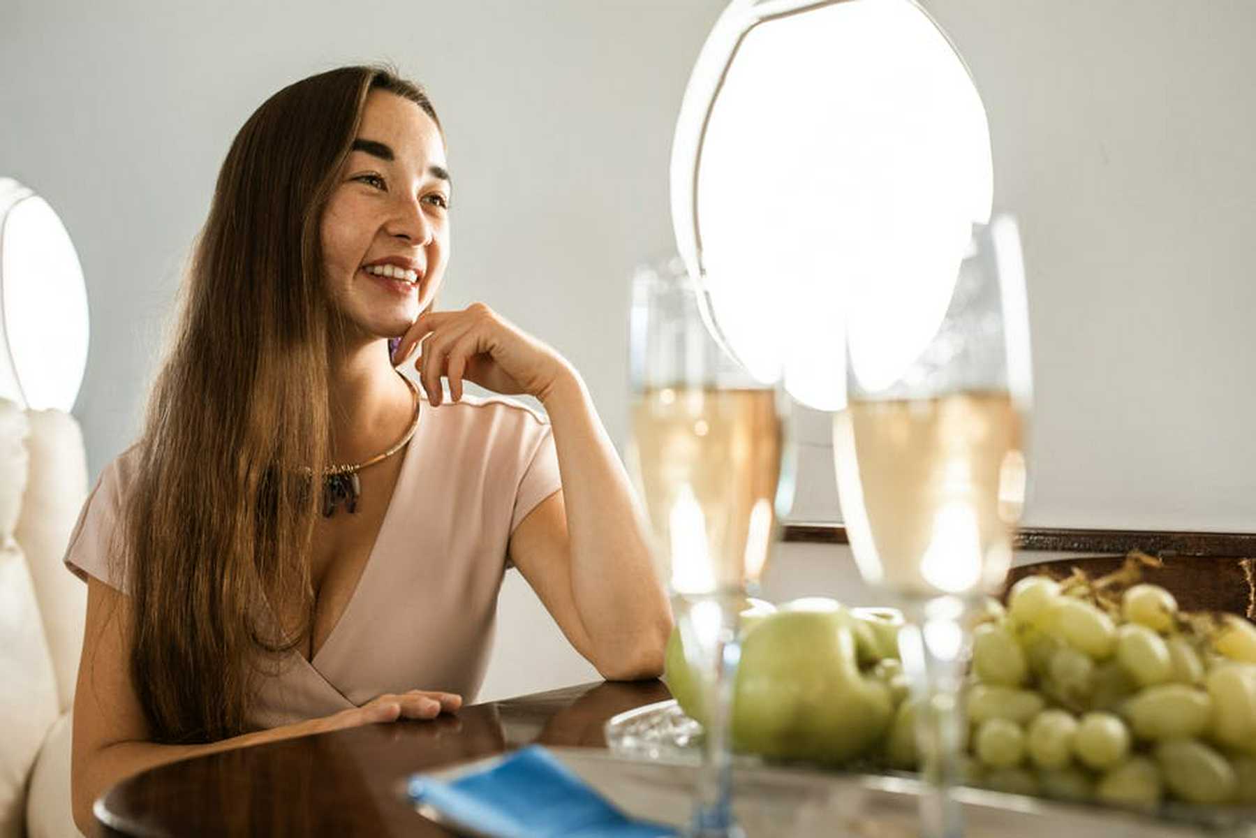 A saleswoman eating champagne and grapes in a private jet