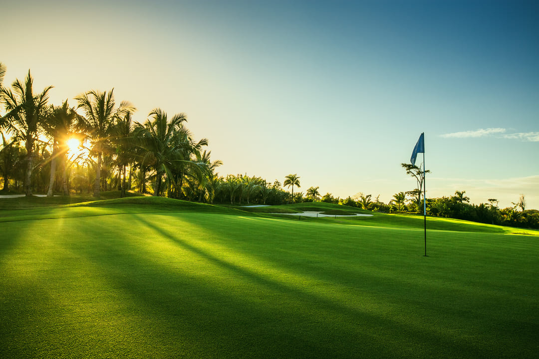 Blick auf ein Pinhole auf dem Grün eines Golfplatzes bei Sonnenuntergang.