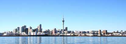 Fotografía de Auckland en Nueva Zelanda. El río en primer plano y los rascacielos del centro de la ciudad con la Sky Tower al fondo.