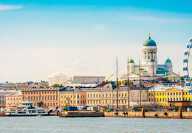 Photo of the city of Helsinki, on the forground, a river with some boats, on the background, the Uspenski Cathedral