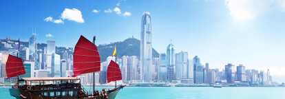 Foto von Hongkong vom Perlfluss aus aufgenommen, links ein Boot mit roten Segeln