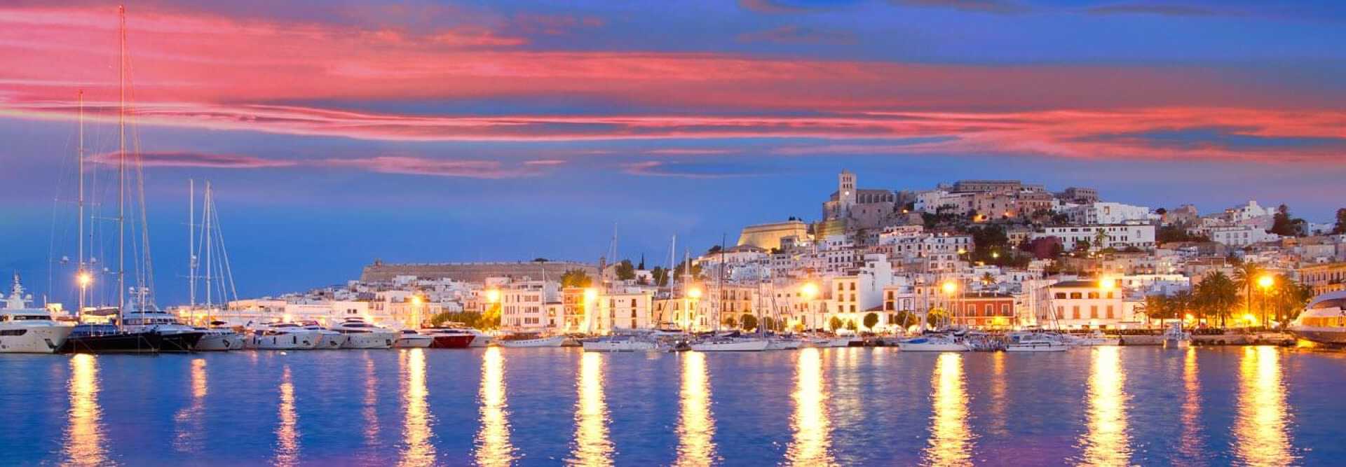 Vue du coucher de soleil depuis les bateaux et les yachts dans le port avec l'église de la ville d'Ibiza