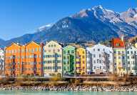 Colourful houses in Innsbruck with the Inn river in foreground and mountains in background
