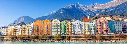 Colourful houses in Innsbruck with the Inn river in foreground and mountains in background