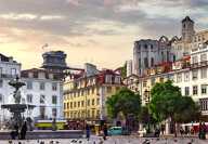 Skyview of Rossio square in Lisbon in the sunset with trees and people walking by