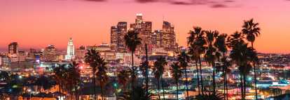 Lo skyline del centro di Los Angeles al tramonto, con il municipio e la Bank of America Plaza illuminati.