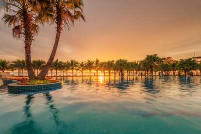 Vue aérienne d'une piscine surplombant l'océan au coucher du soleil à la Barbade, dans les Caraïbes