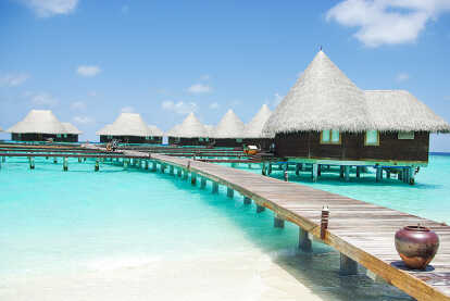 View of a beach in the Maldives with a hotel on stilts above turquoise water