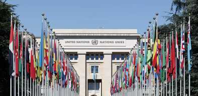 United Nations building in Geneva by a sunny day with the flags of member states United Nations building in Geneva by a sunny day with the flags of member states