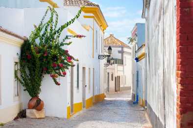 Calle estrecha con casas de colores claros en Faro