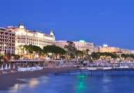 A private beach in Cannes by night with the illuminated Intercontinental Carlton palace on the Croisette