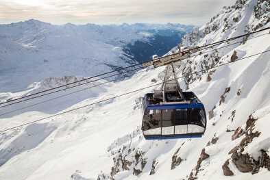 Die Seilbahnkabine der Valluga mit Touristen gegen verschneite Klippen