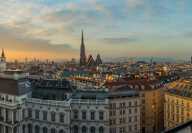 Luftaufnahme der Dächer von Wien in Österreich bei Sonnenuntergang. Im Hintergrund eine Kathedrale