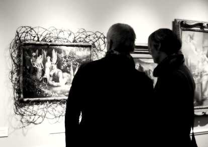 Couple looking at a extraordinary framed painting with a donkey headed human at TEFAF Maastricht