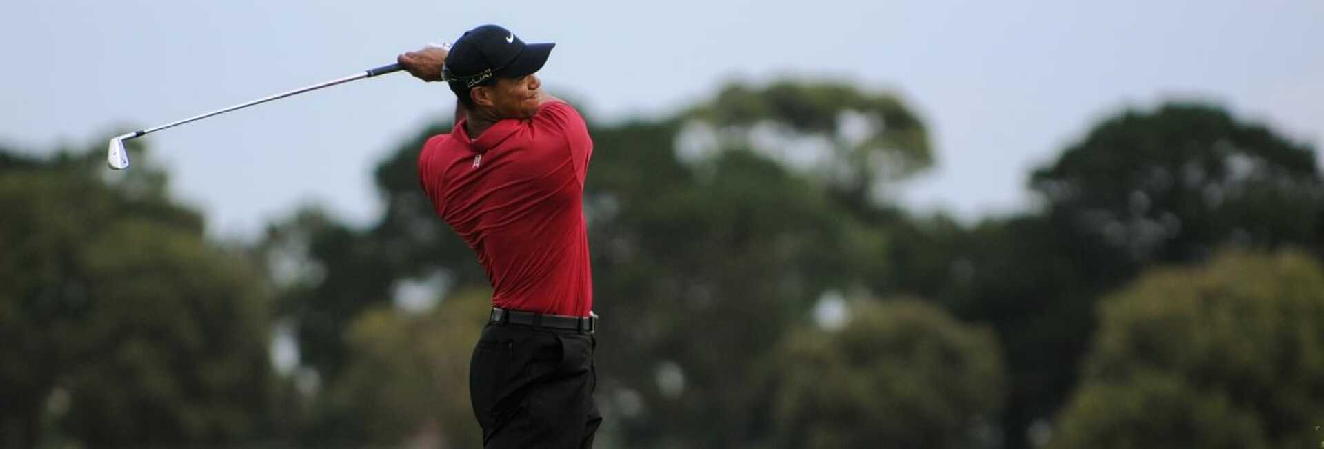 Tiger Woods playing golf with a red polo black trousers and Nike cup at the US Masters