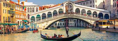 Gondola with tourists in front of the Rialto bridge illustrating the Venice Biennale in Italy