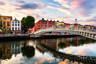 Dublin, Irland. Nachtansicht der berühmten beleuchteten Ha Penny Bridge in Dublin, Irland bei Sonnenuntergang