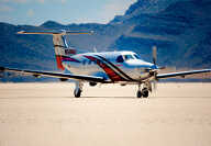 Blue Pilatus PC-12 turboprop with white drowing flying over Swiss snowy mountains