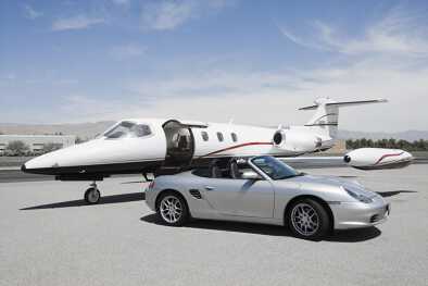 Jet privato con porta aperta e Porsche all'aeroporto.