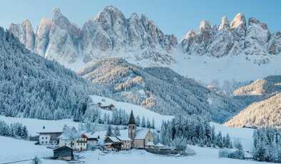 Небольшая деревня Валь-ди-Фунес, покрытая снегом, на фоне Доломитовых гор, Южный Тироль, Италия.
