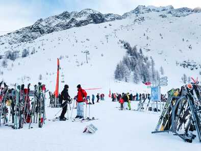 Люди катаются на лыжах, груда лыж и вид на склоны в зоне катания Les Grands Montets недалеко от Шамони, Франция