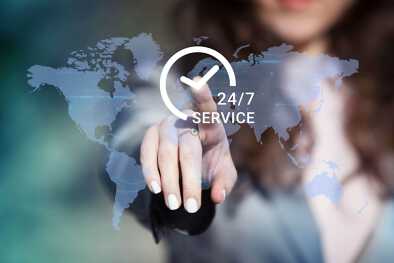Empresaria presionando el botón de asistencia técnica 24/7 en el mapa mundial en pantalla táctil.  Concepto de servicio al cliente.