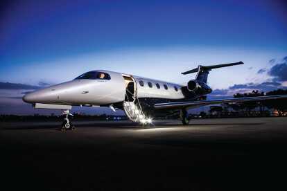 Embraer Jet Phenom 300E on airfield at night with stairs folded out