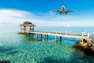 Un jet privato che vola vicino a un molo di un'isola esotica su acque turchesi Un jet privato che vola vicino a un molo di un'isola esotica su acque turchesi