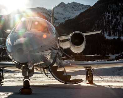 Primo piano del muso di un elegante business jet sullo sfondo di montagne invernali