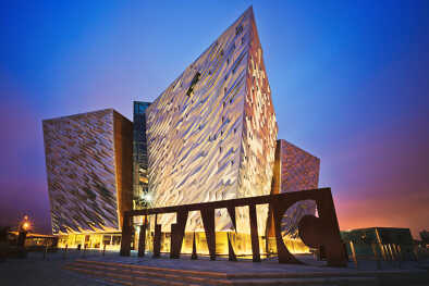 Puesta de sol sobre el Titanic Belfast: museo, atracción turística y monumento al patrimonio marítimo de Belfast en el emplazamiento del antiguo astillero Harland and Wolff.